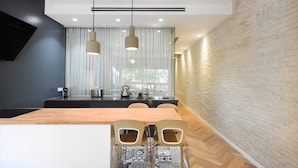 A modern kitchen with a wooden island, pendant lights, and a brick accent wall.