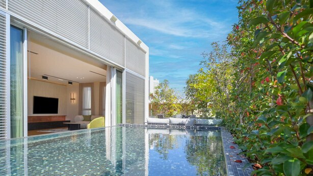 Un hôtel moderne doté d’une piscine à débordement en verre, d’un jardin bien entretenu et d’un design intérieur contemporain.