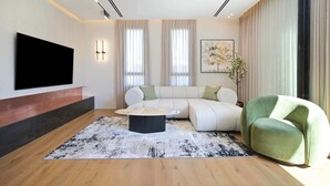 Un salon moderne avec un canapé d’angle, une table basse ronde et un fauteuil vert.
