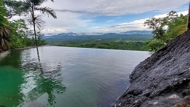 A infinity pool with a view of mountains and greenery.