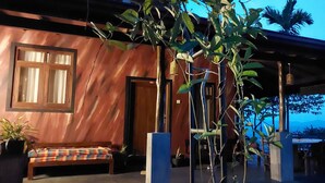 A wooden building with a bench and potted plants.