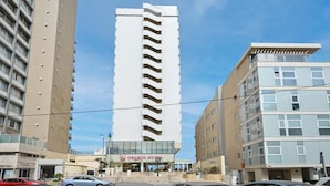 Un hotel moderno con una torre central, varios balcones y cielo despejado.