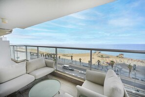 A balcony with a view of the beach and the sea.