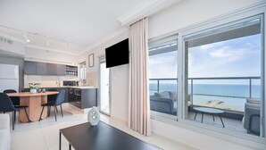 Una habitación de hotel moderna con balcón, comedor y cocina.