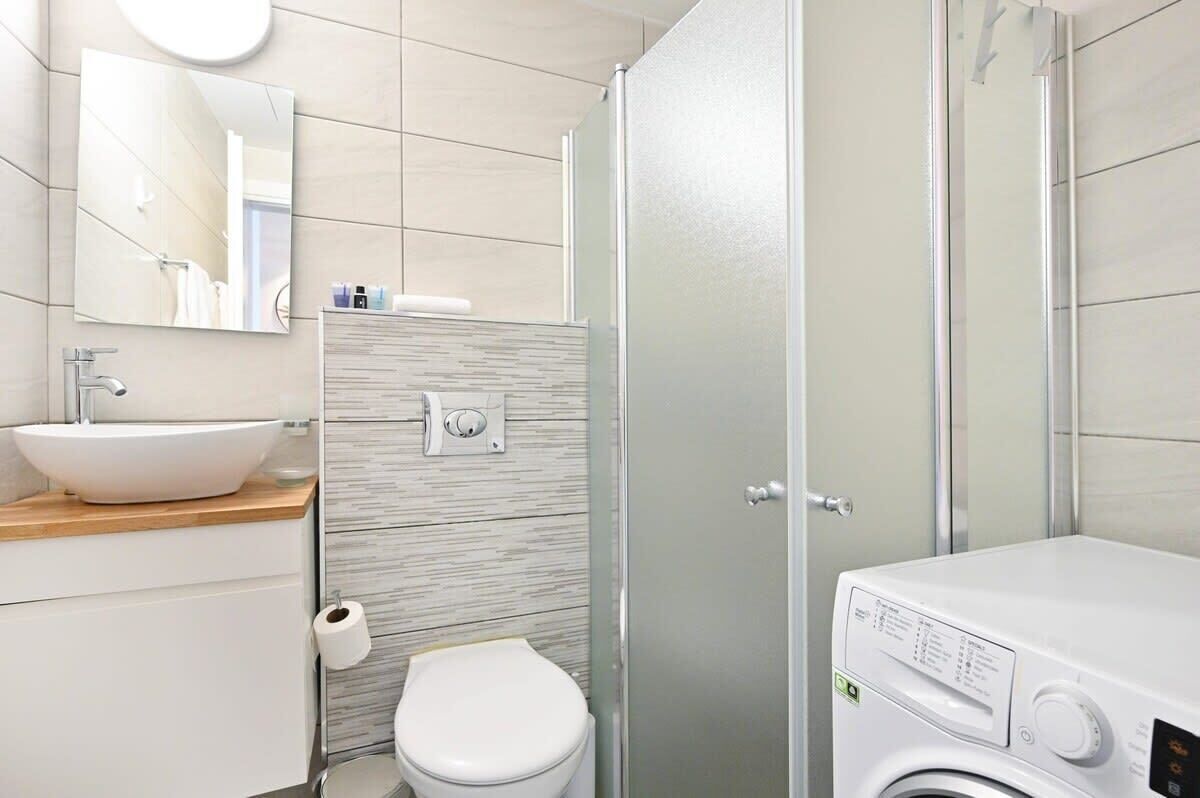 Une salle de bain moderne équipée d’un lavabo, de toilettes et d’un lave-linge encastré.