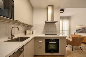 A modern kitchen with a built-in oven, a dishwasher, and a stainless steel range hood.