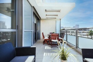 Un balcón con comedor y zona de estar, con vistas a un paisaje urbano.
