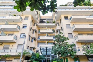 A multi-story residential building with balconies, a central entrance, and surrounding greenery. - Splendor 2-BR  in Melchet  by HolyGuest (Tel Aviv)