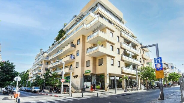 Un edificio de varios pisos con balcones, una tienda y un paso de peatones.