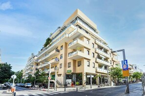 Un immeuble à plusieurs étages doté de balcons, d’une devanture de magasin et d’un passage piéton.