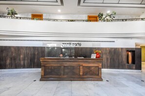 A reception desk with a wooden finish, a glass window, and a sign above it.