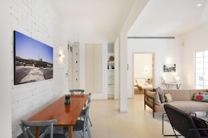 Una sala de estar moderna con una mesa y sillas de madera, un sofá y un ventanal grande.