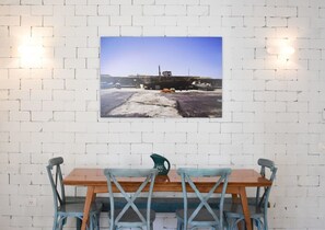 A dining area with a brick wall, a framed photograph, and a wooden table with blue chairs. - Spacious 3BR at Mapu st by HolyGuest (Tel Aviv)