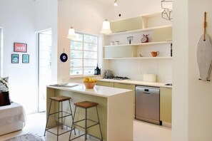 A modern kitchen with a central island, bar stools, and a dishwasher.