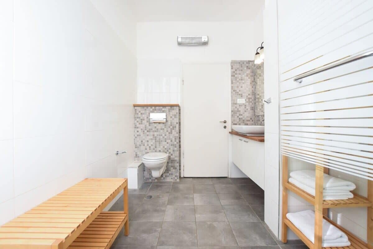 Un baño moderno con inodoro, lavamanos y un banco de madera.
