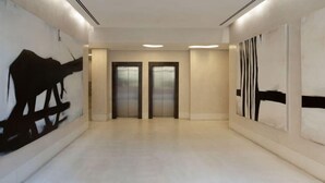 A hallway with two doors, a light-colored floor, and abstract wall art.