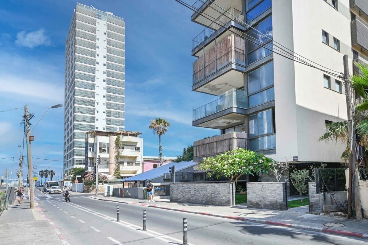 Eine moderne Stadtstraße mit Hochhäusern, blauem Himmel und einer Fußgängerampel.