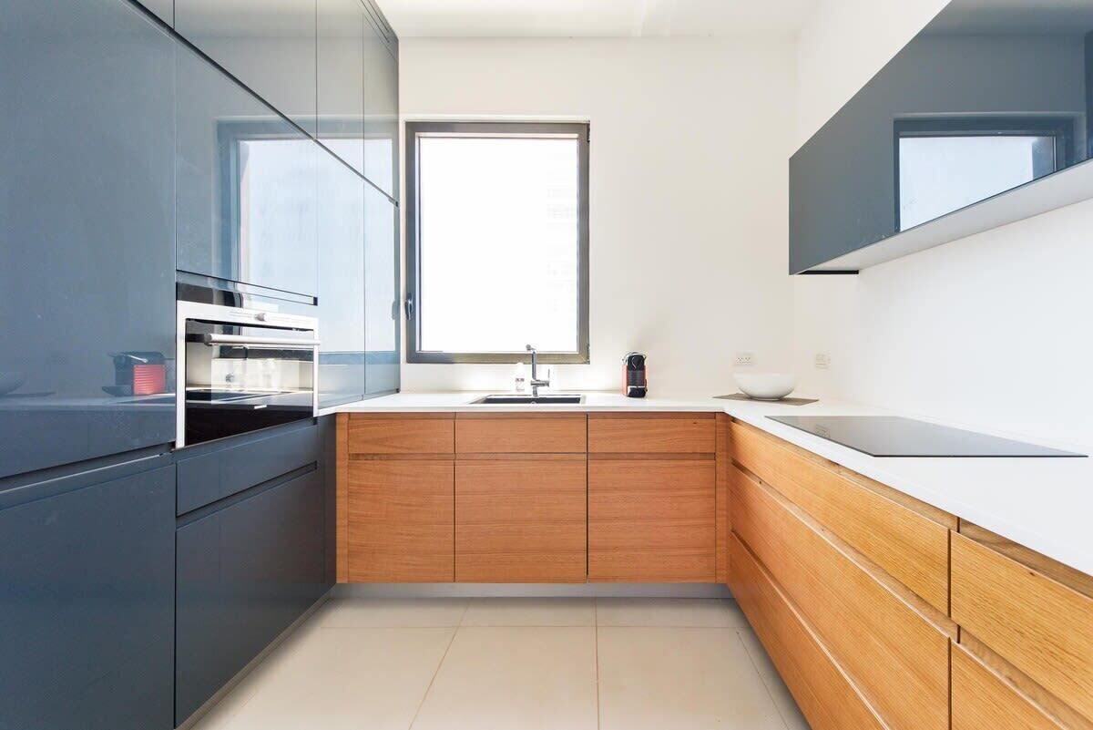 Una cocina moderna con armarios oscuros, una encimera de madera y una ventana sobre el fregadero.