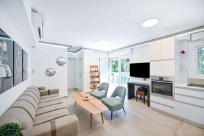 A modern living room with a sofa, chairs, a coffee table, and a TV. - Bright 2BR Apartment with Balcony in Dizengoff by HolyGuest (Tel Aviv-Yafo)