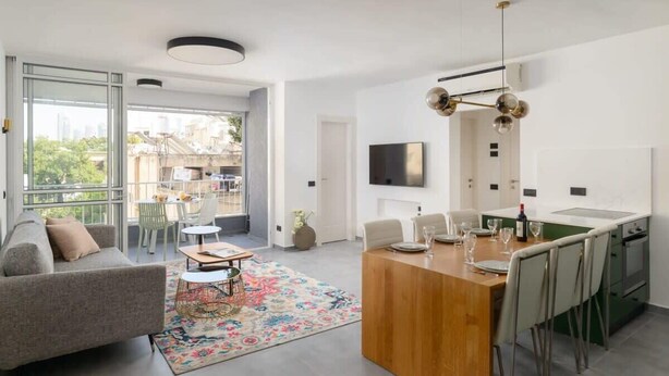 A modern apartment with a dining area, kitchen, and a balcony with a city view.