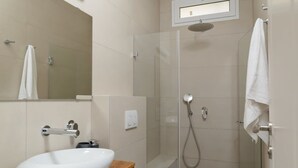 A modern bathroom with a white sink, a glass shower enclosure, and a toilet.
