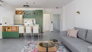 A modern living space with a kitchen, dining area, and a grey sofa.