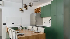 A modern kitchen with a central island, green cabinets, and a stainless steel refrigerator.