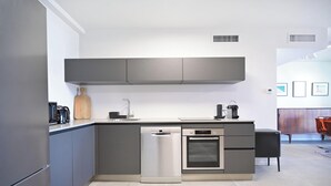 A modern kitchen with grey cabinetry, a dishwasher, an oven, and a coffee maker.