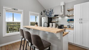 Een moderne keuken met een houten kookeiland, witte kasten en uitzicht op de omgeving.