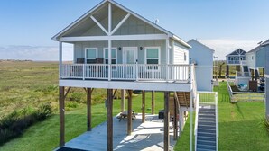 Een huis aan de kust met een balkon, terras en uitzicht op het strand.