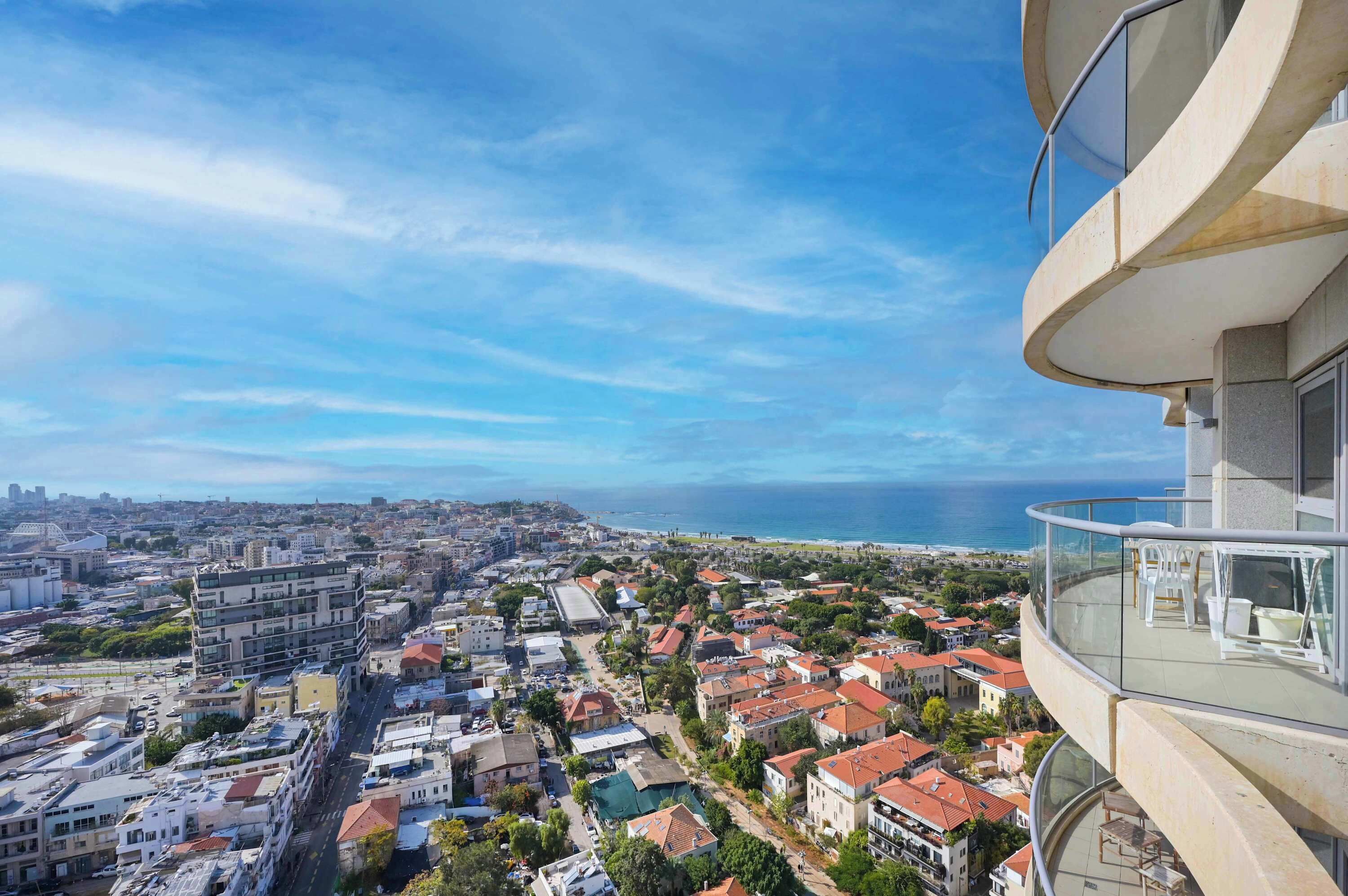 Een hoog gebouw met een glazen balkon met uitzicht op een stadsgezicht aan de kust.