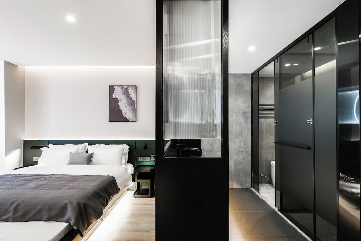 A modern hotel room with a large bed, a nightstand, a TV, and a sliding door closet.