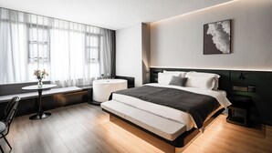 A modern hotel room with a large bed, bedside tables, a round table with chairs, a window with sheer curtains, and a wall-mounted artwork. - Liya Hotel Futian Free Trade Zonam (Shenzhen)