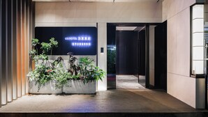 A modern hotel lobby with a reception desk, potted plants, and a sign indicating the hotel's name. - Liya Hotel Futian Free Trade Zonam (Shenzhen)