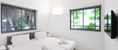 Une chambre moderne avec deux lits, de grandes fenêtres, un téléviseur à écran plat et une table de chevet.