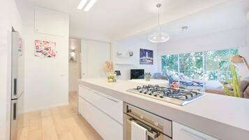 A modern kitchen with a central island, built-in oven, and a large window offering a view of the outdoors.
