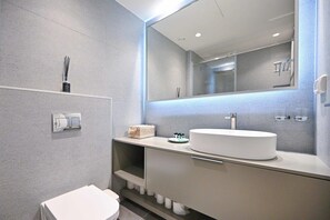 Ein modernes Badezimmer mit großem Spiegel, weißem Waschbecken und Toilette.