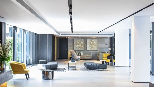 Een ruime, moderne lobby met een centraal zitgedeelte, grote ramen en een eigentijdse inrichting.