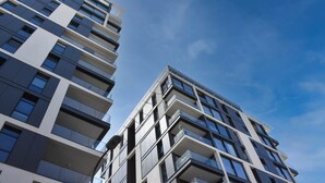 Een modern hoog gebouw met meerdere balkons en grote ramen.