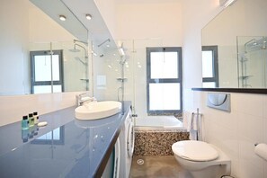 A modern bathroom with a glass shower enclosure, a bathtub, a toilet, and a large mirror. - Charming 2BD in Gordon by HolyGuest (Tel Aviv)