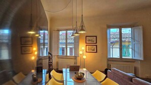 A dining area with a table, chairs, a laptop, and a bowl. There are windows with shutters and a radiator. - Apartment in the Center of Florence With a View (Florence)