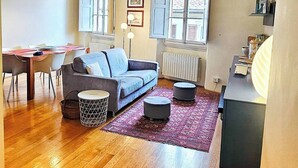 A living room with a sofa, a dining table, and a kitchen area with a radiator. - Apartment in the Center of Florence With a View (Florence)