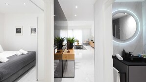 A modern hotel room with a bed, a desk with plants, a round mirror, and a bathroom with a sink and mirror. - Outer Space at Hayarkon by HolyGuest (Tel Aviv-Yafo)