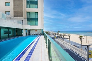 Un hotel con piscina, vista al mar y fachada de edificio moderna.