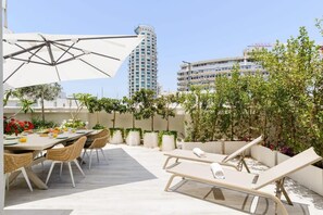 A rooftop terrace with a dining area, lounge chairs, and potted plants.