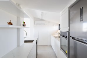 Een moderne keuken met witte kasten, een roestvrijstalen koelkast en een oven.