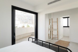Une chambre moderne avec une grande fenêtre, un lit, une échelle en bois et une vue sur le paysage urbain.