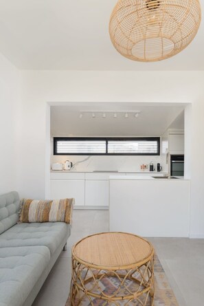 Een moderne keuken met witte kastjes, een inbouwoven en een raam boven de aanrecht.