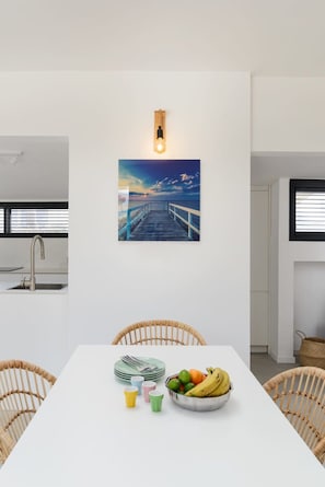Een moderne keuken met een wit aanrecht, een rvs-spoelbak en een houten lijst rondom een foto boven het aanrecht.