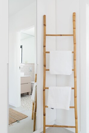 A bathroom with a bamboo towel rack holding two white towels.